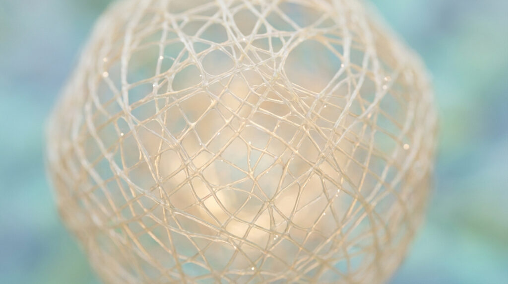 Gros plan d'un réseau complexe de fibres entrelacées couleur crème sur fond flou bleu-vert. Représente la structure de la fibrine.